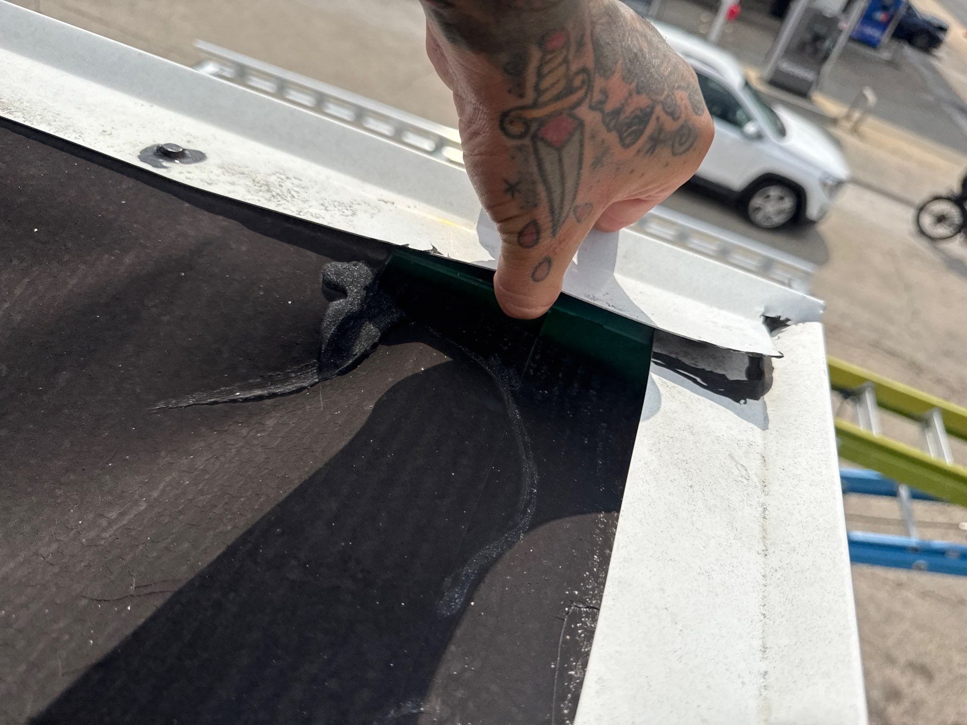 A hand indicating a separated membrane seam at the roof edge.