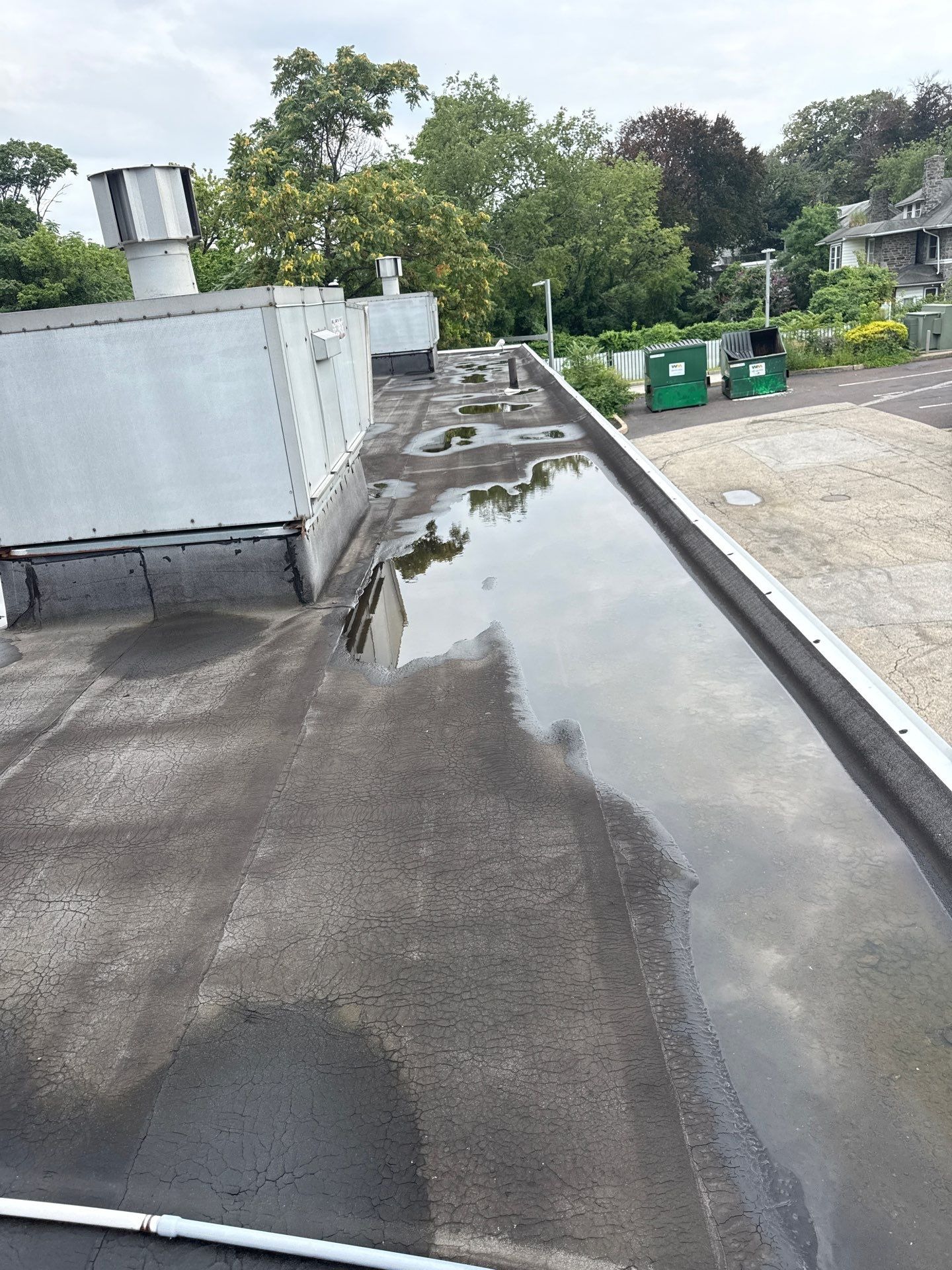 Wide view of the low-slope roof with standing water pooled around rooftop equipment.